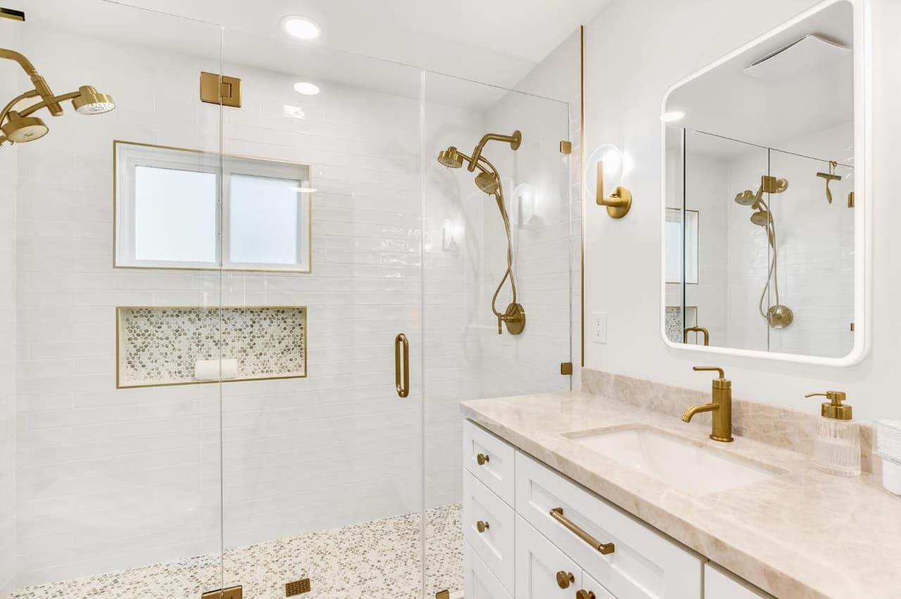 House Renovation in Davis — frameless glass shower, tiled shower surround, handheld shower, single vanity, lighted mirror