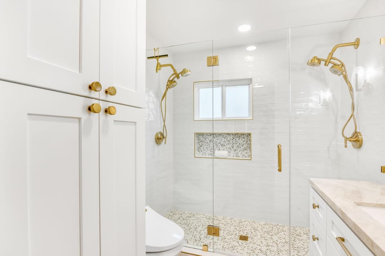 House Renovation in Davis — frameless glass shower, tiled shower surround, handheld shower, recessed lighting, linen tower