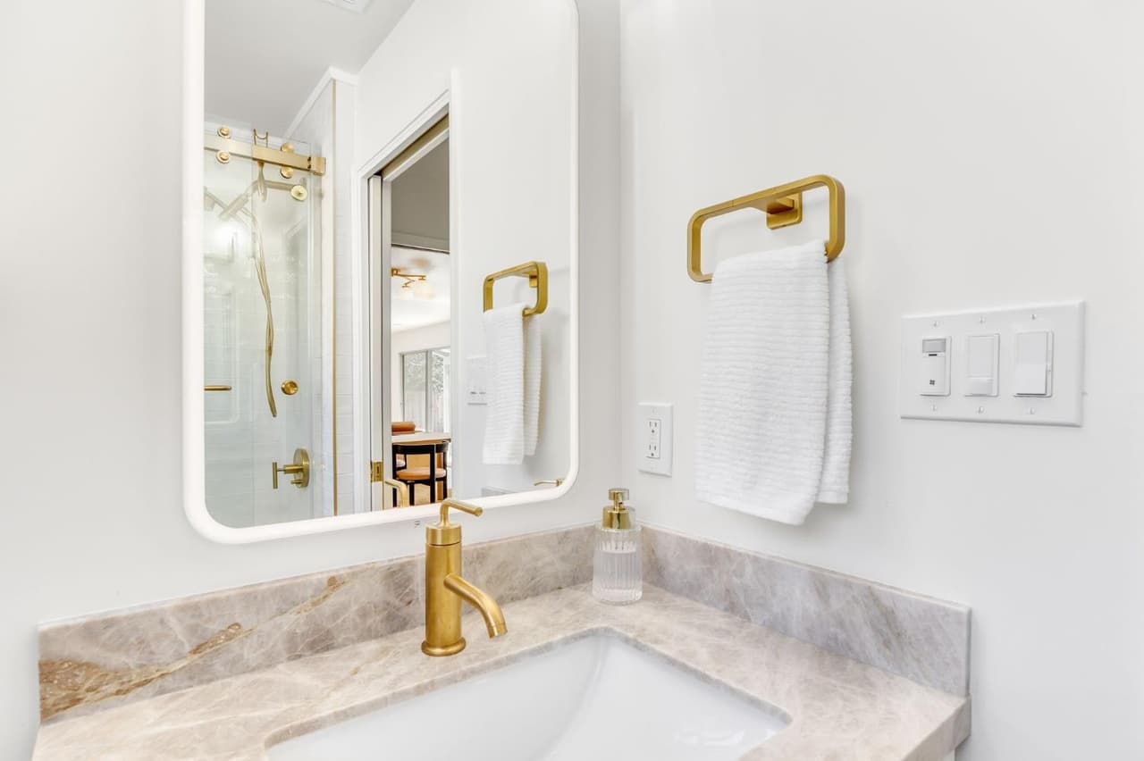 House Renovation in Davis — lighted mirror, undermount sink, marble countertop, single vanity, frameless glass shower