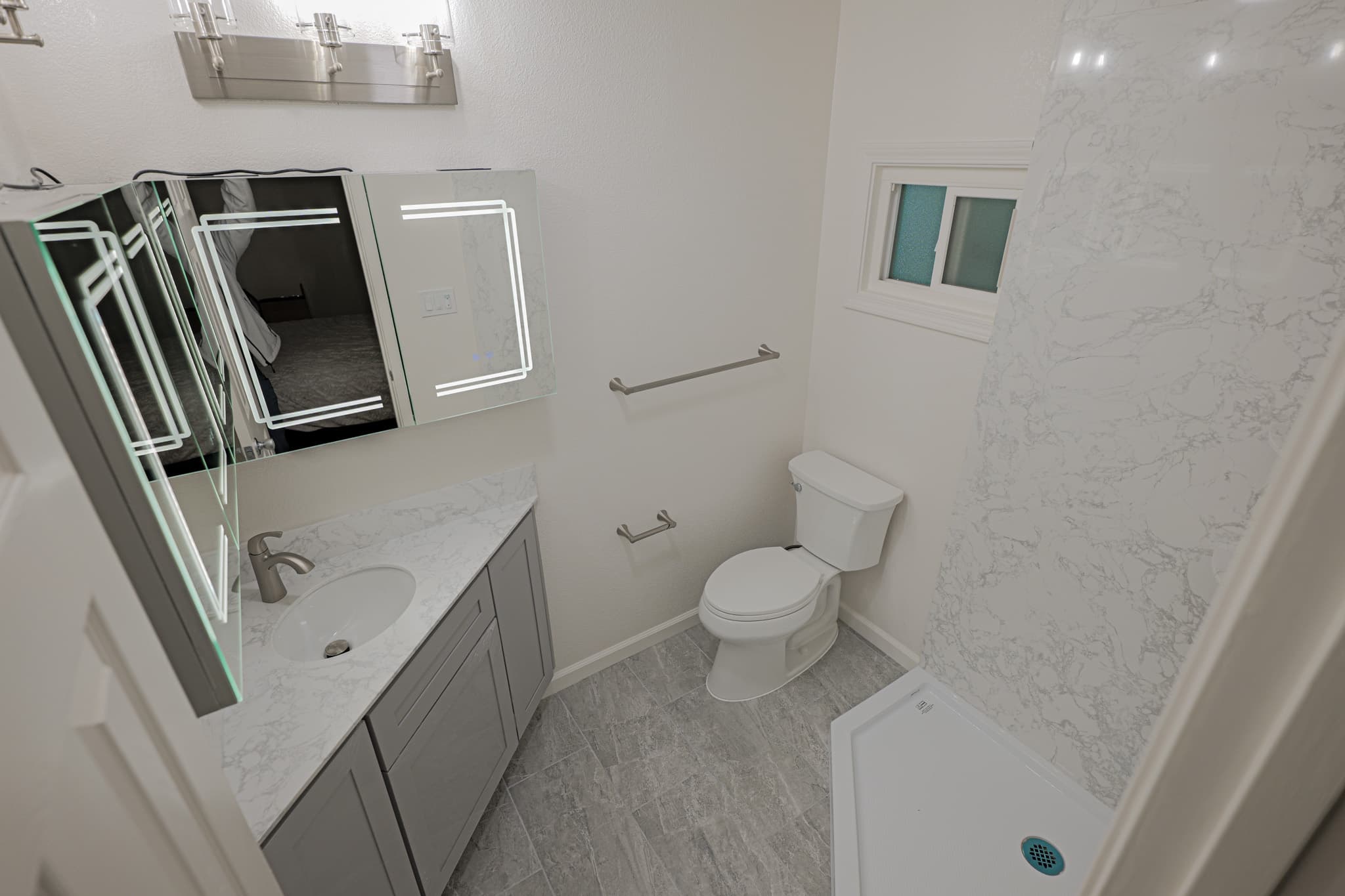 House Renovation in Sacramento — single vanity, lighted mirror, walk-in shower, tiled shower surround, porcelain tile flooring