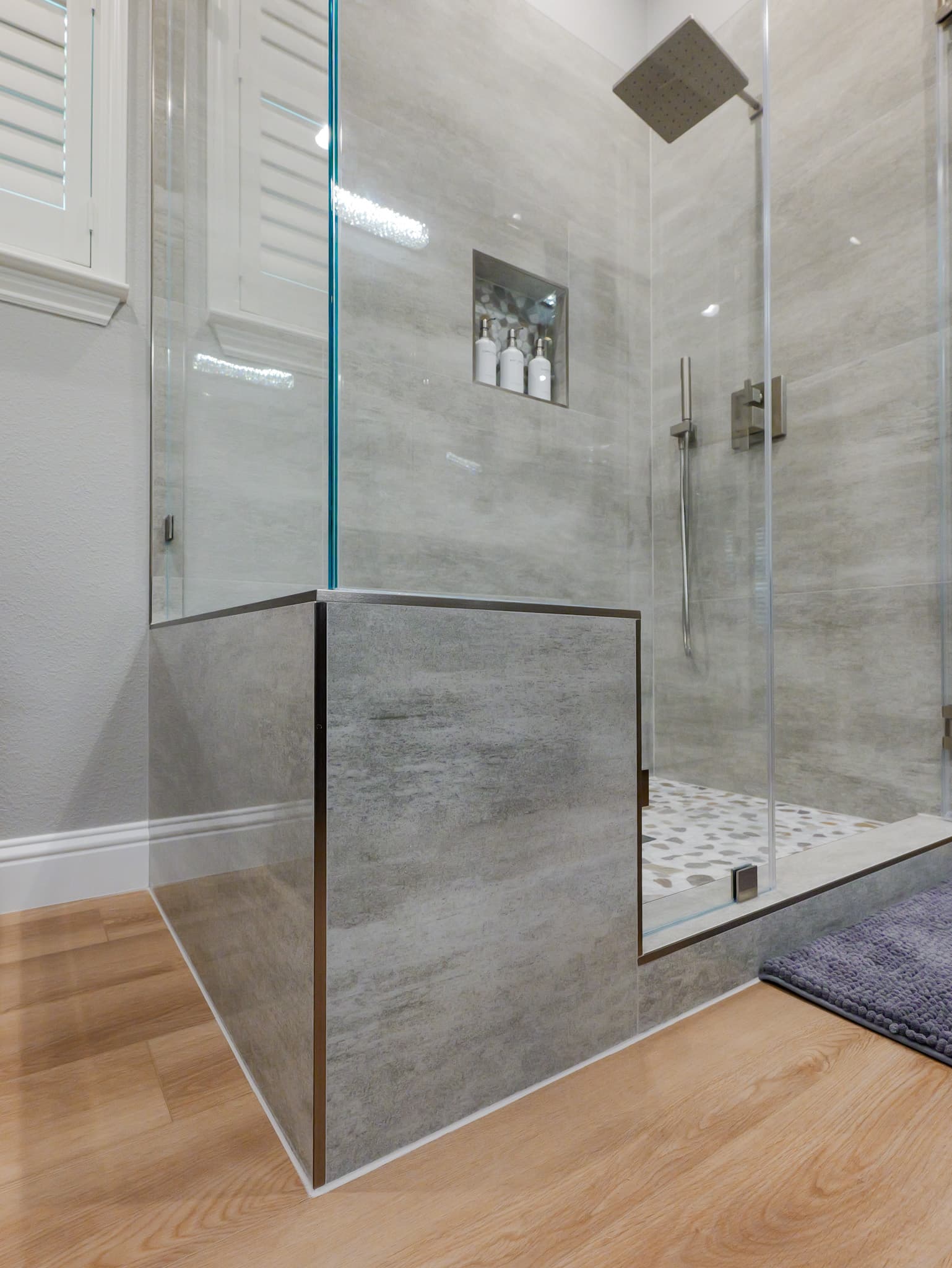 Bathroom Remodel in Roseville — frameless glass shower, tiled shower surround, rain shower head, handheld shower, hardwood flooring