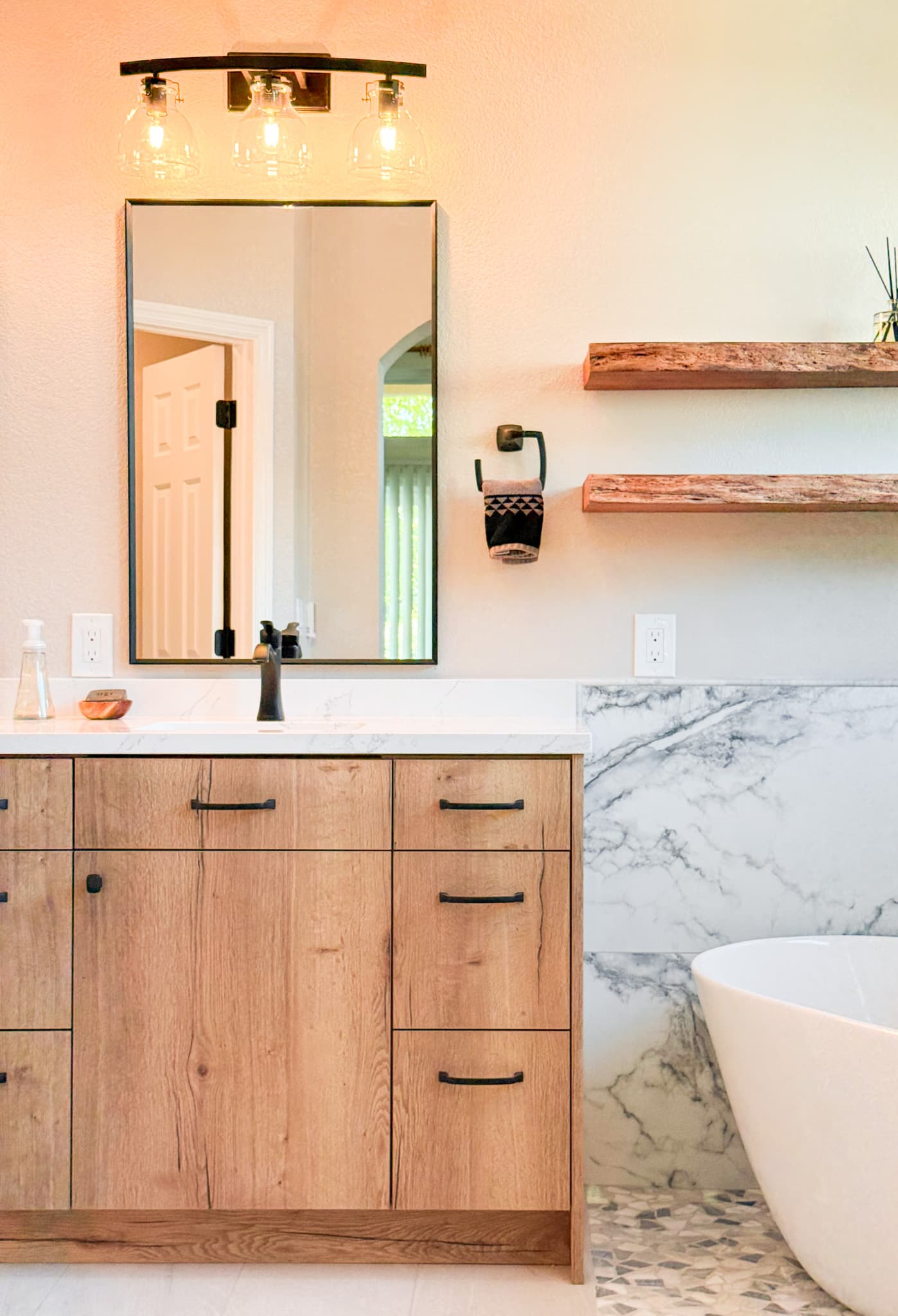 Bathroom Remodel in El Dorado Hills — single vanity, freestanding tub, marble countertop, natural-stone backsplash, framed mirror
