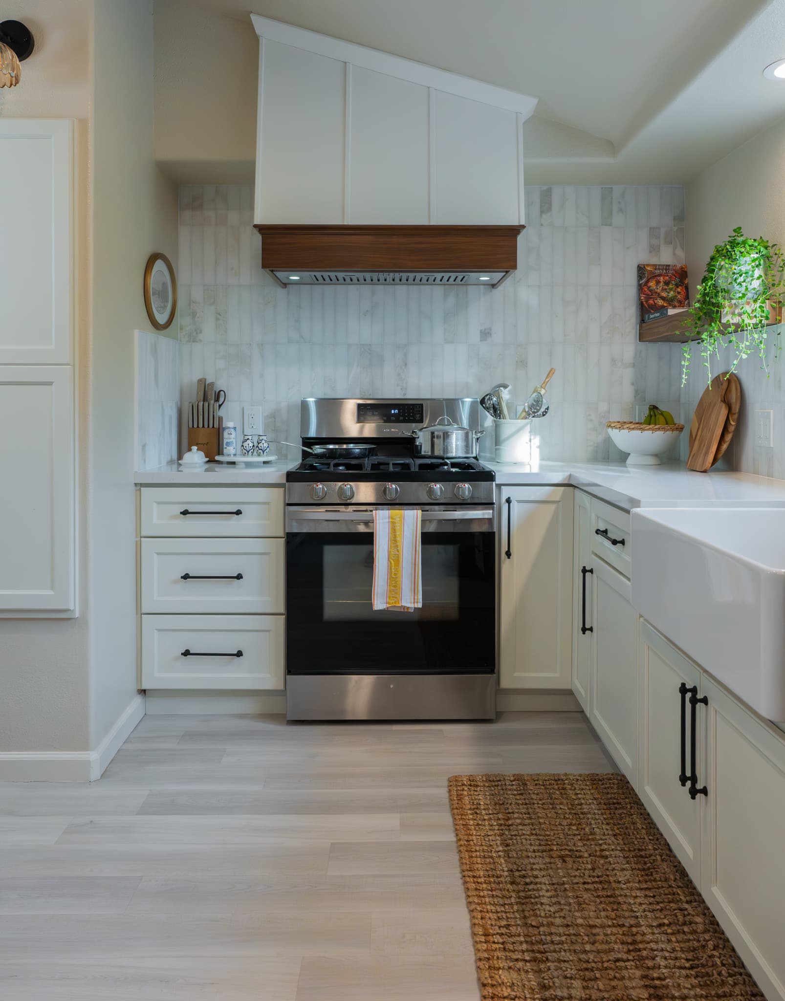 Kitchen Remodel in Rocklin — raised-panel cabinets, range hood, professional gas range, natural-stone backsplash, luxury vinyl plank