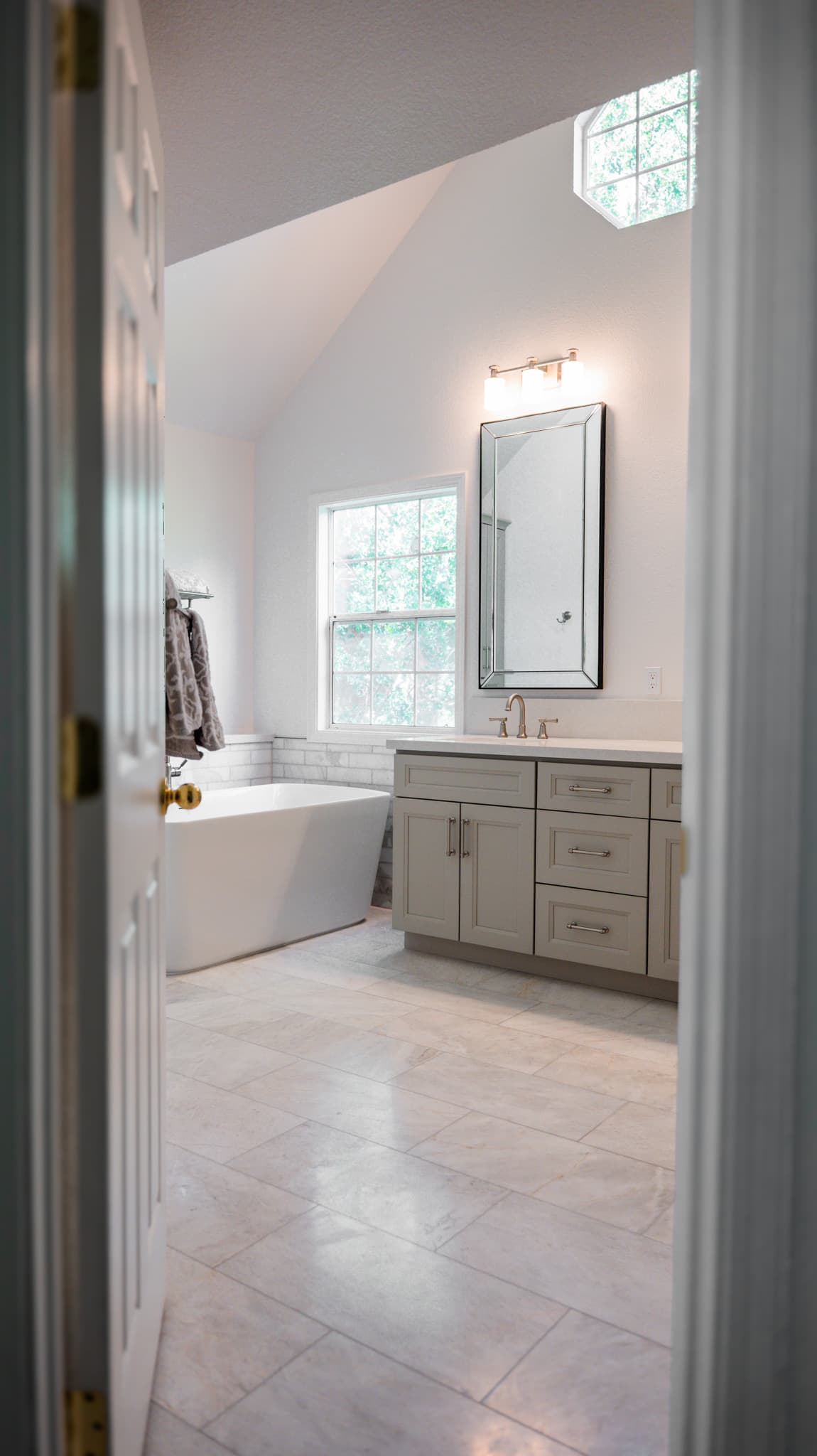 Bathroom Remodel in Sacramento — freestanding tub, single vanity, framed mirror, marble tile flooring, vaulted ceiling