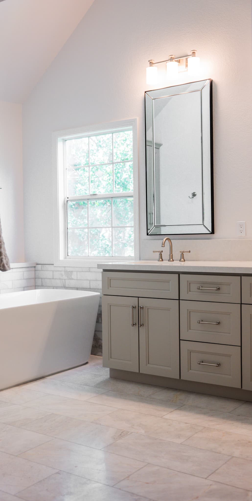 Bathroom Remodel in Sacramento — freestanding tub, single vanity, framed mirror, marble tile flooring, subway tile backsplash