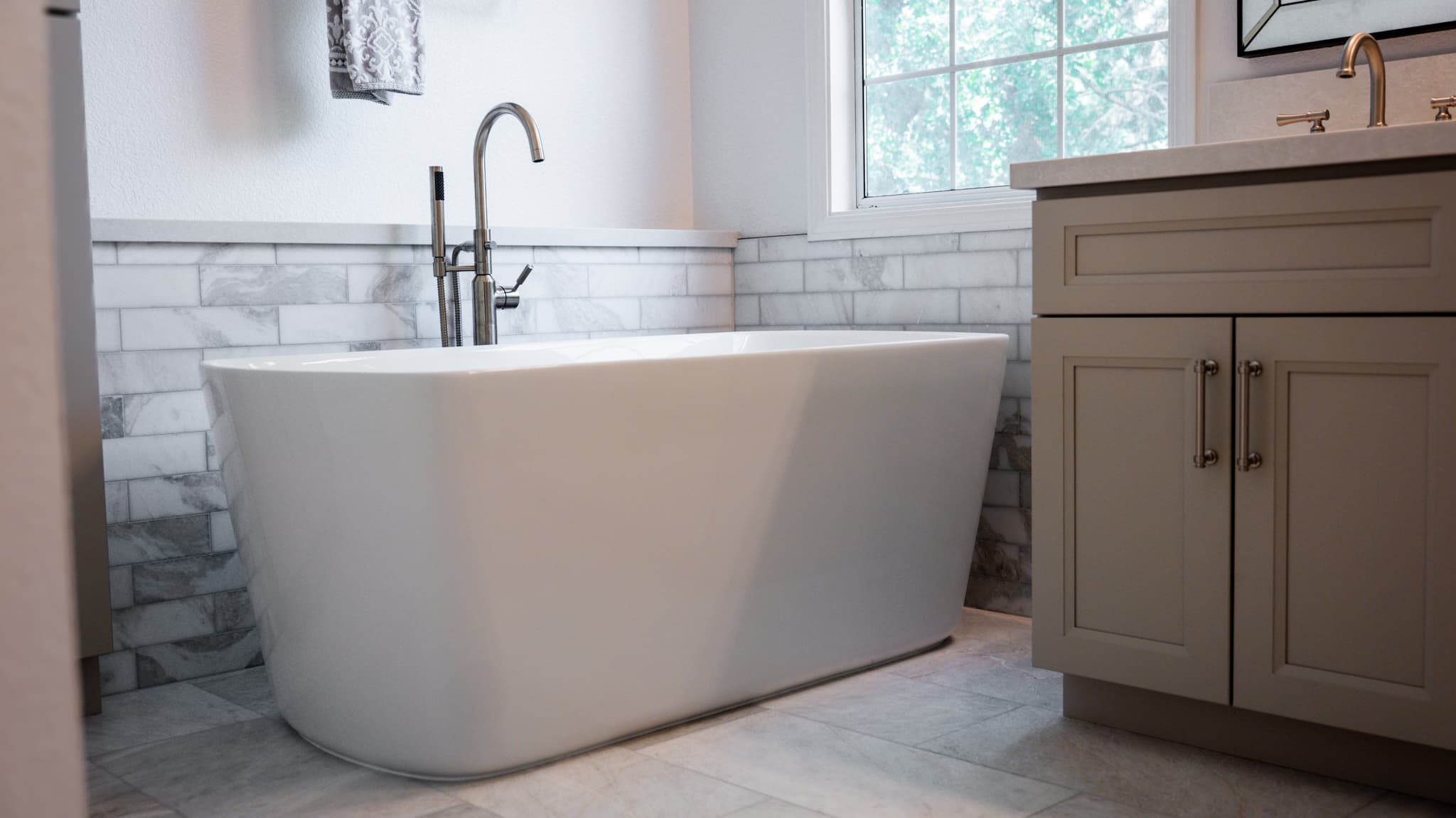 Bathroom Remodel in Sacramento — freestanding tub, natural-stone backsplash, marble tile flooring, shaker cabinets, handheld shower