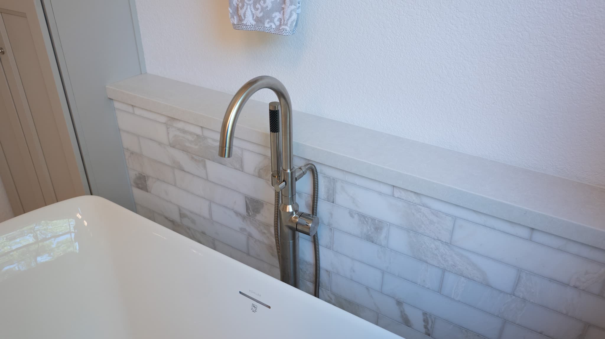 Bathroom Remodel in Sacramento — freestanding tub, soaking tub, handheld shower, natural-stone backsplash, marble tile flooring