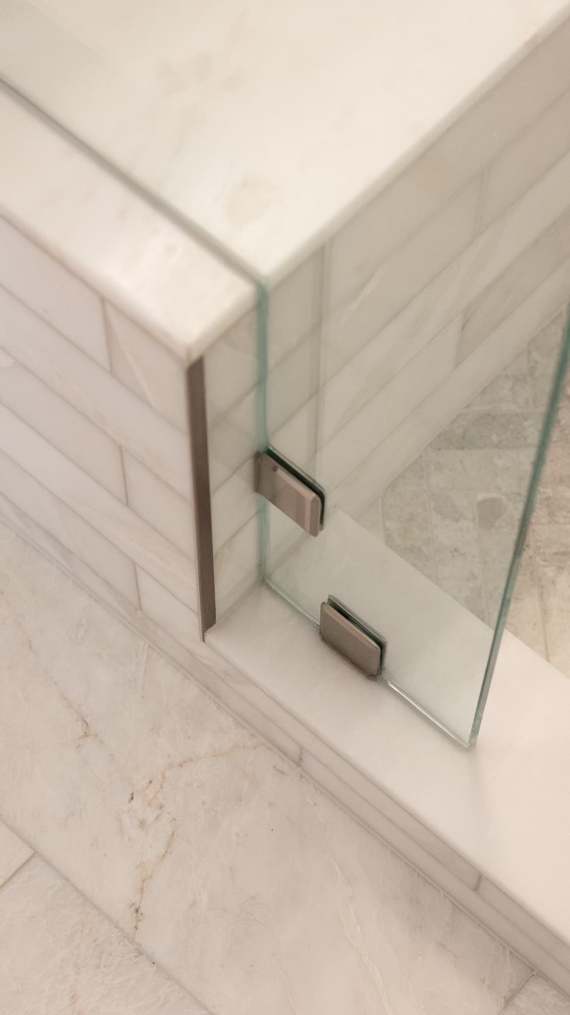 Bathroom Remodel in Sacramento — frameless glass shower, tiled shower surround, marble tile flooring, natural-stone backsplash, shower bench