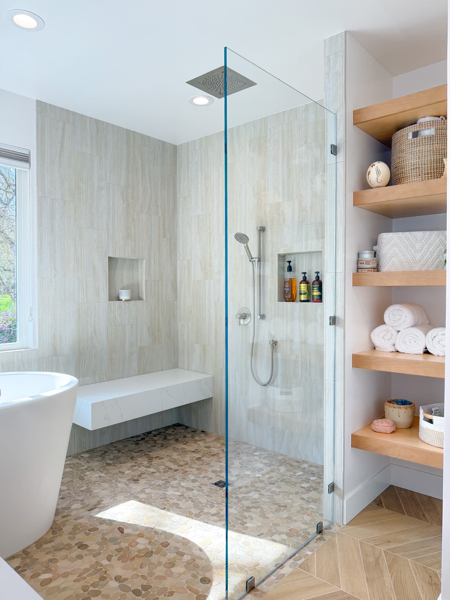 Bathroom Remodel in Carmichael — frameless glass shower, tiled shower surround, shower bench, rain shower head, freestanding tub