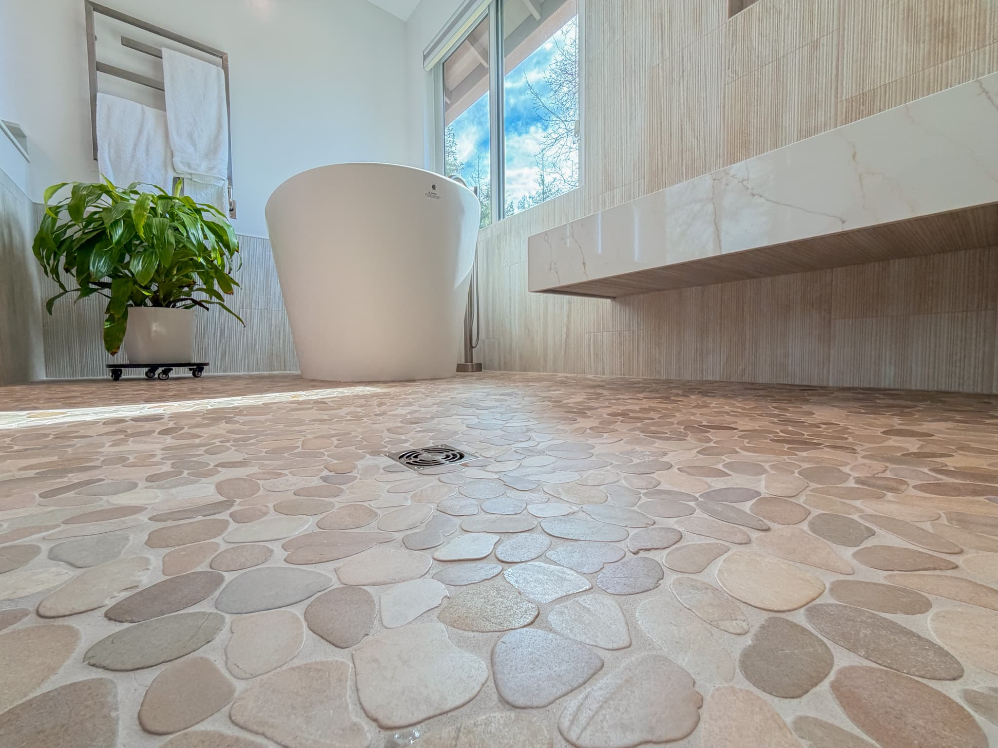 Bathroom Remodel in Carmichael — freestanding tub, natural-stone tile flooring, floating vanity, marble countertop, handheld shower