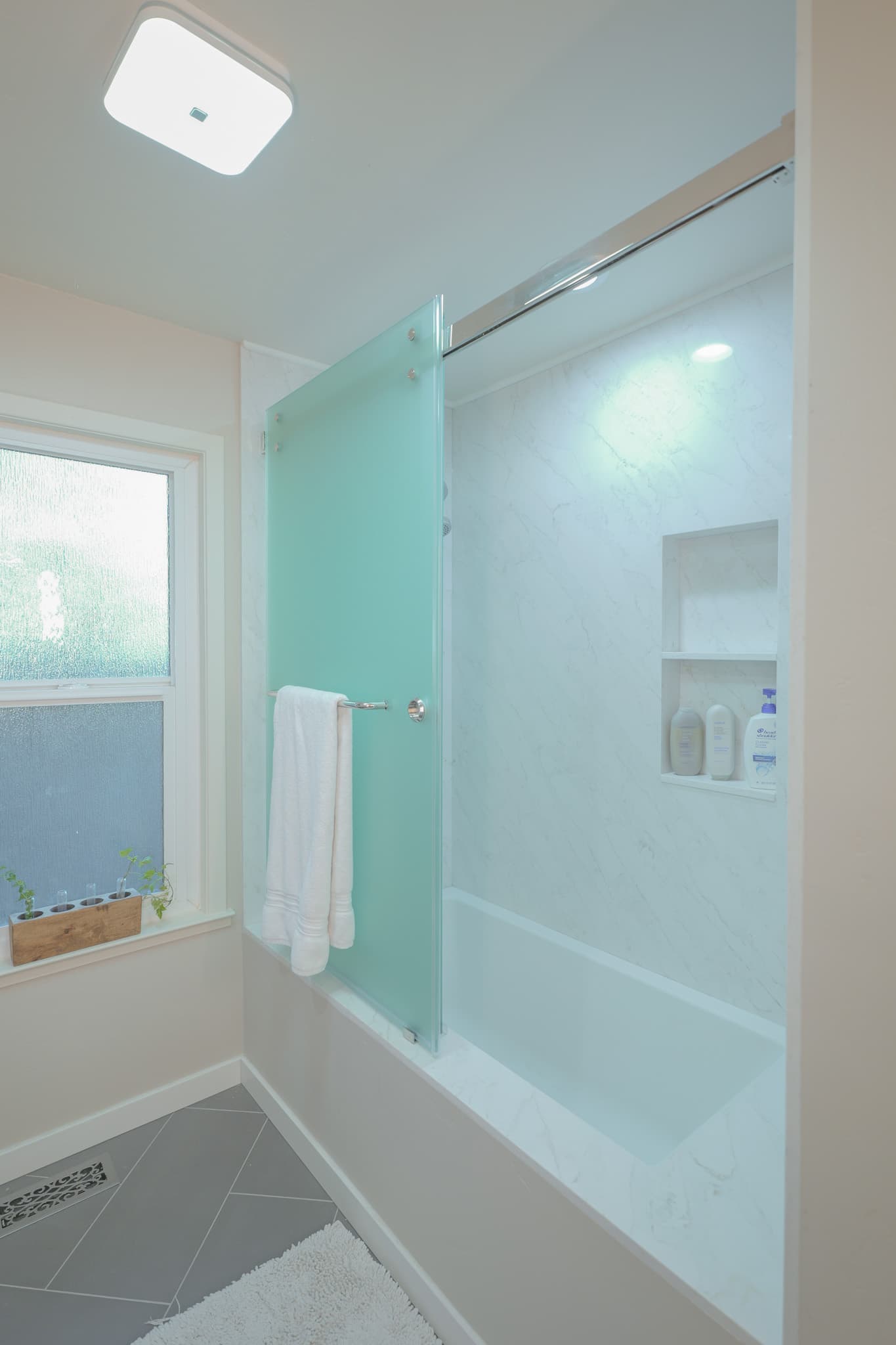House Renovation in Sacramento — frameless glass shower, tiled shower surround, soaking tub, built-in shelving, porcelain tile flooring