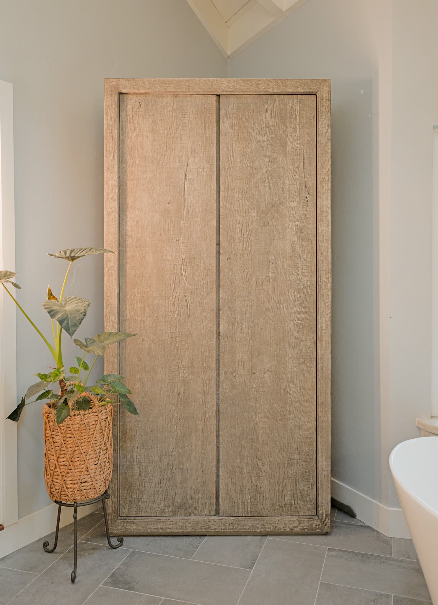 House Renovation in Sacramento — linen tower, porcelain tile flooring, freestanding tub, vaulted ceiling, custom cabinetry