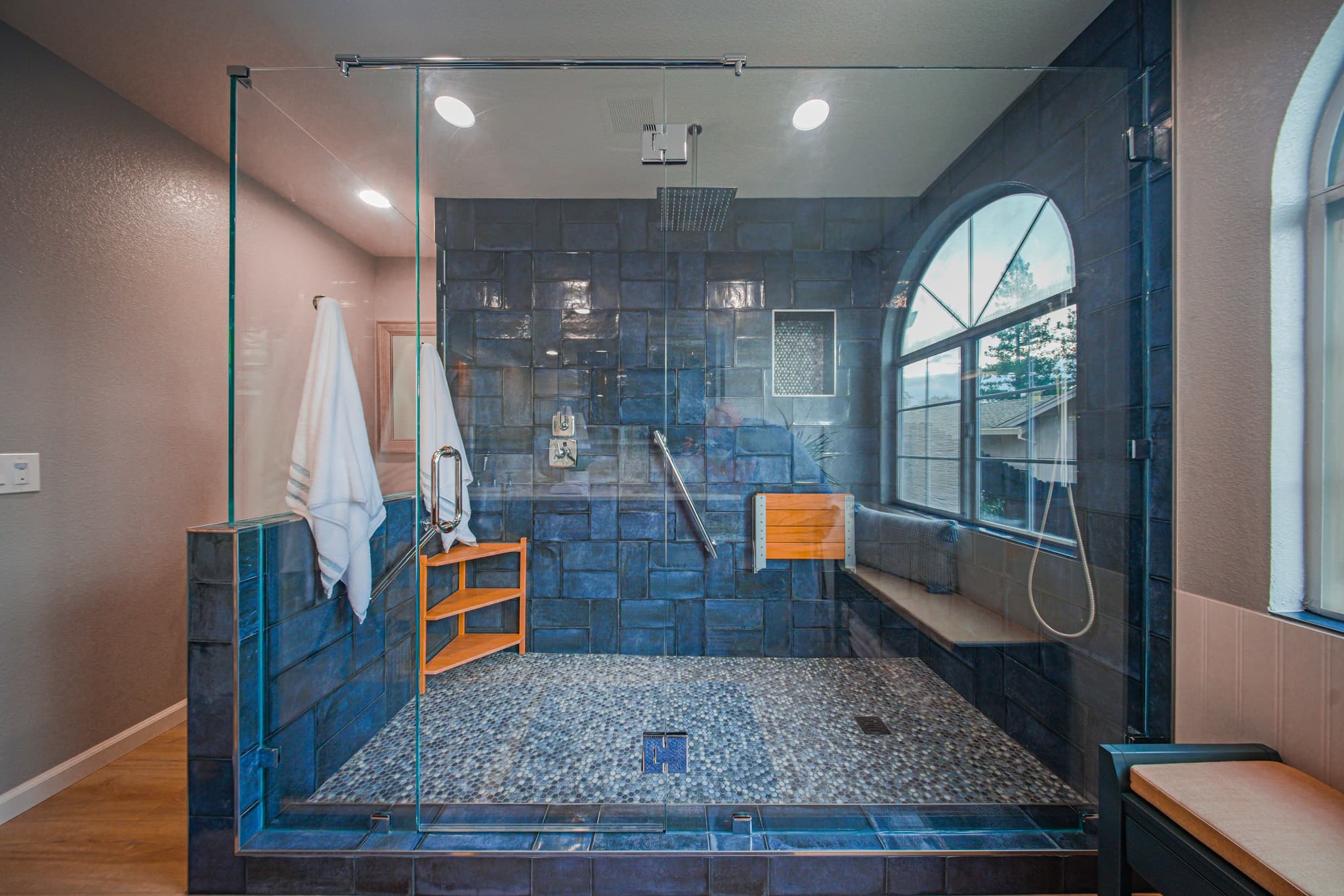 Bathroom Remodel in Sacramento — frameless glass shower, tiled shower surround, rain shower head, handheld shower, shower bench