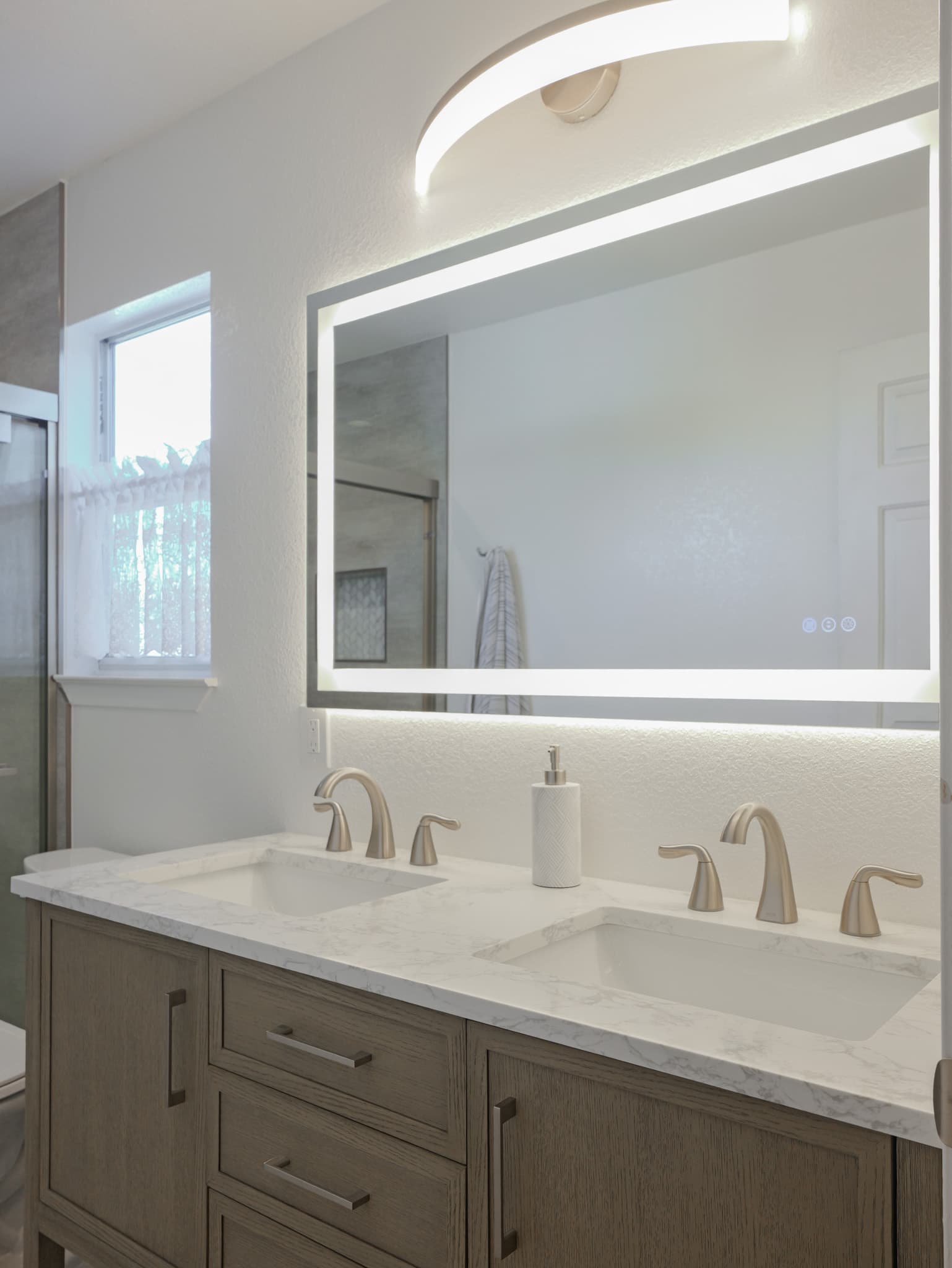 Bathroom Remodel in Sacramento — double vanity, lighted mirror, undermount sink, quartz countertop, frameless glass shower